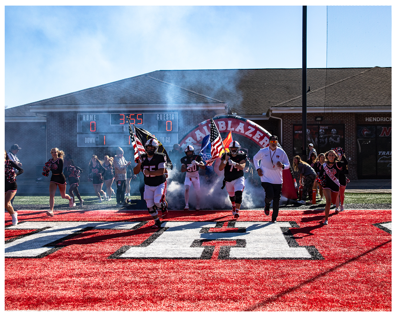 Football team running onto the field with smoke and flags